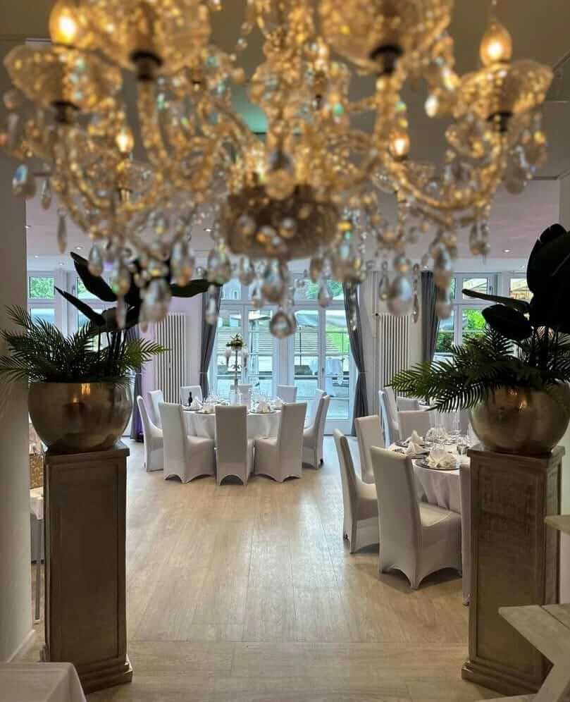 Eleganter Speisesaal mit weiß gedeckten Tischen und funkelndem Kronleuchter